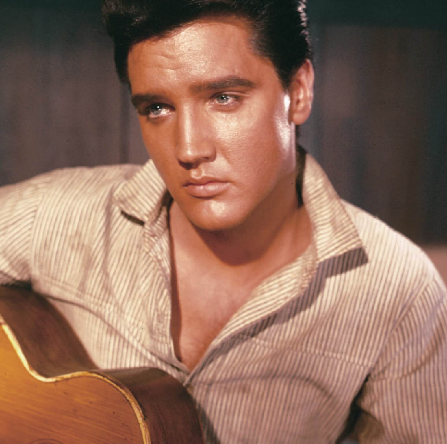 Elvis Presley, a singer mentioned in Marc Cohn's 'Walking in Memphis," with a guitar