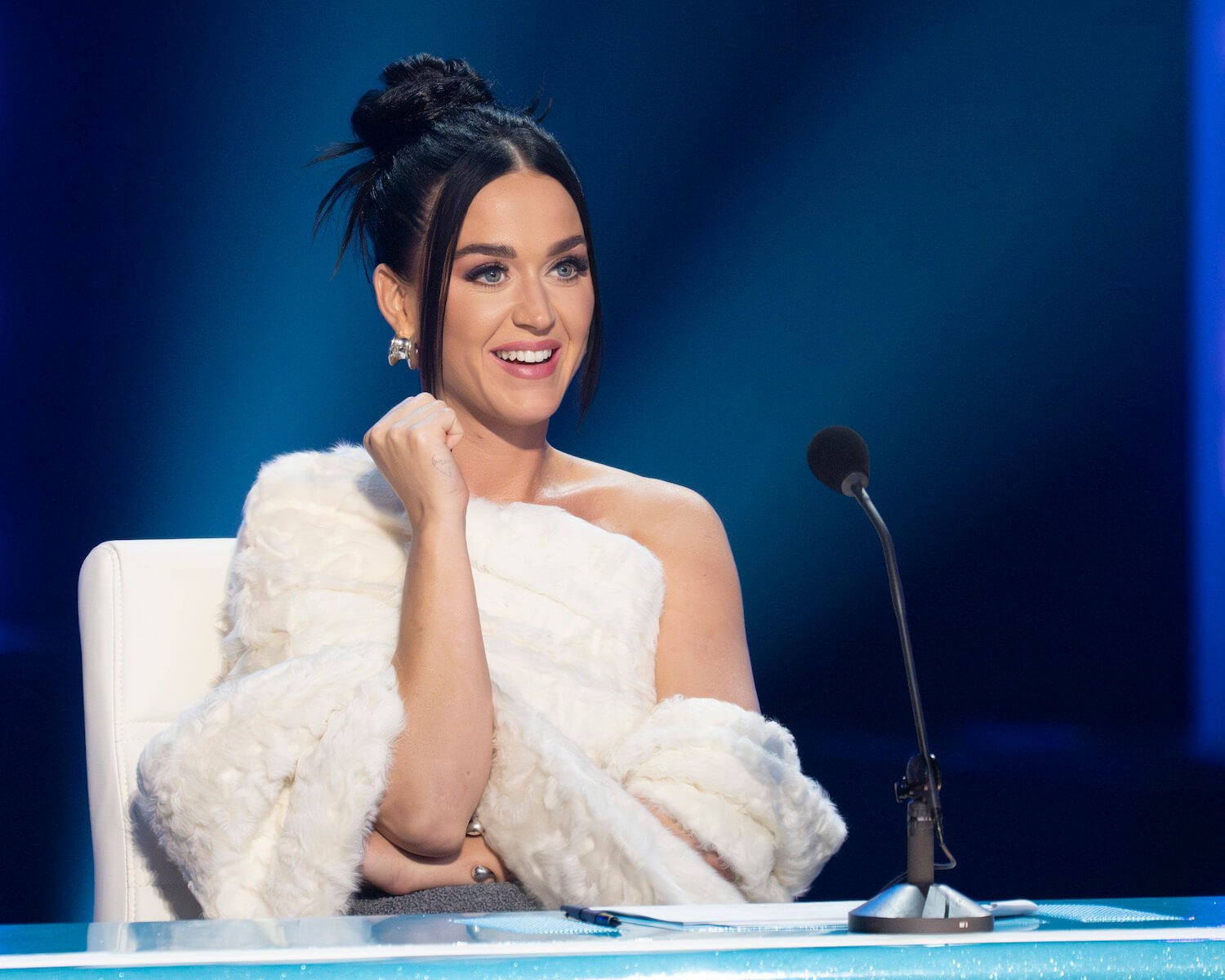 'American Idol' Season 22 judge Katy Perry wearing a white furry outfit while sitting at the judges table