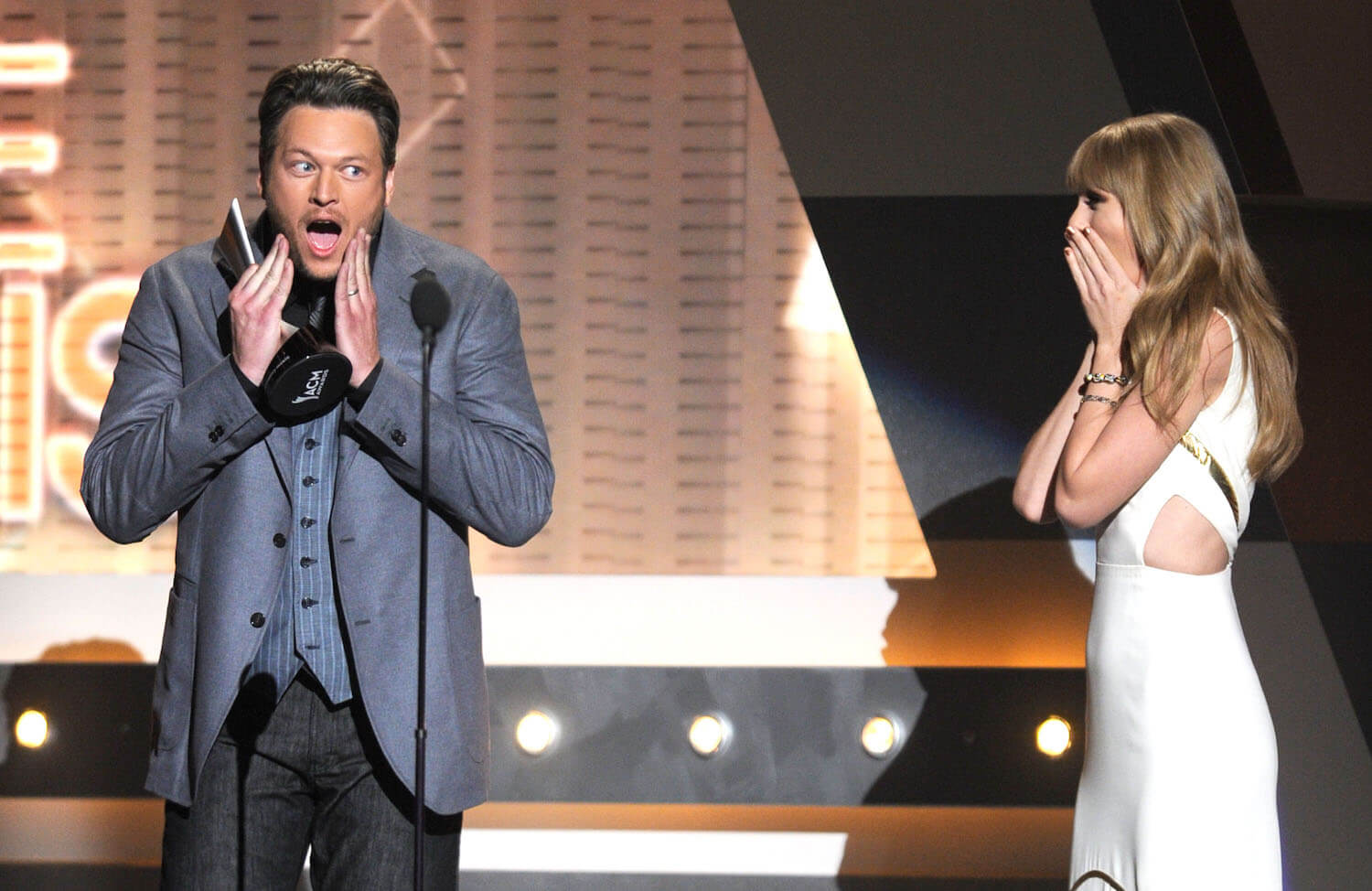 Blake Shelton holding his face in surprise while receiving an award from Taylor Swift, who also looks surprised, at the 47th Annual Academy of Country Music Awards in 2012
