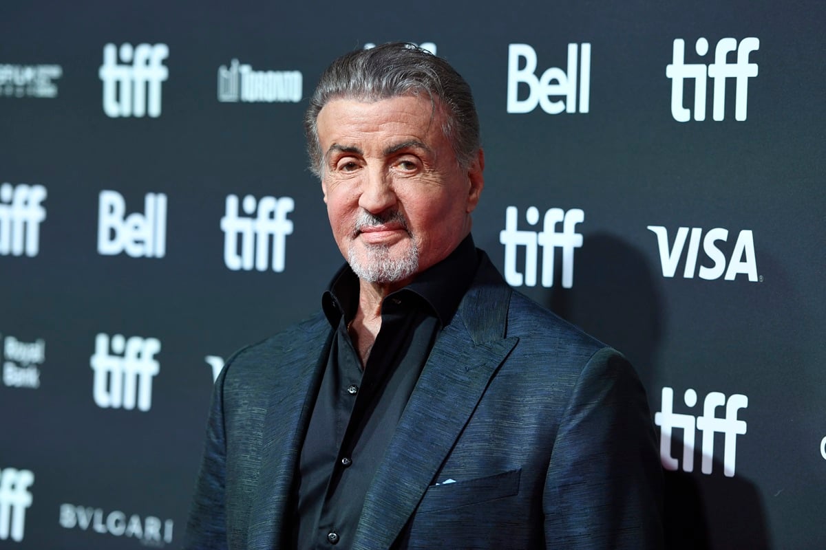 Sylvester Stallone posing in a black suit.