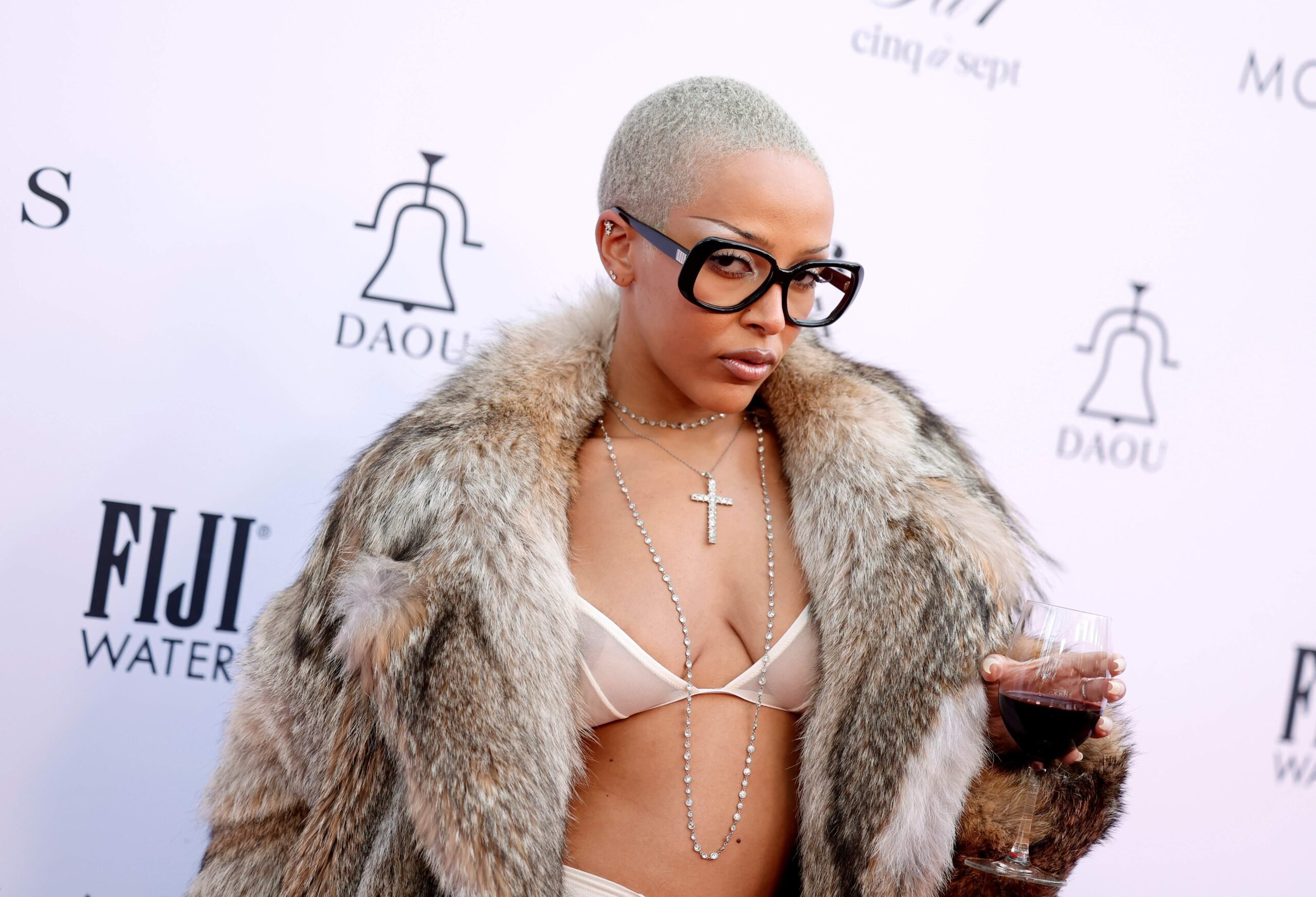 Rapper/singer Doja Cat holds a glass of wine as she walks the red carpet in a fur coat at The Daily Front Row's Eighth Annual Fashion Los Angeles Awards