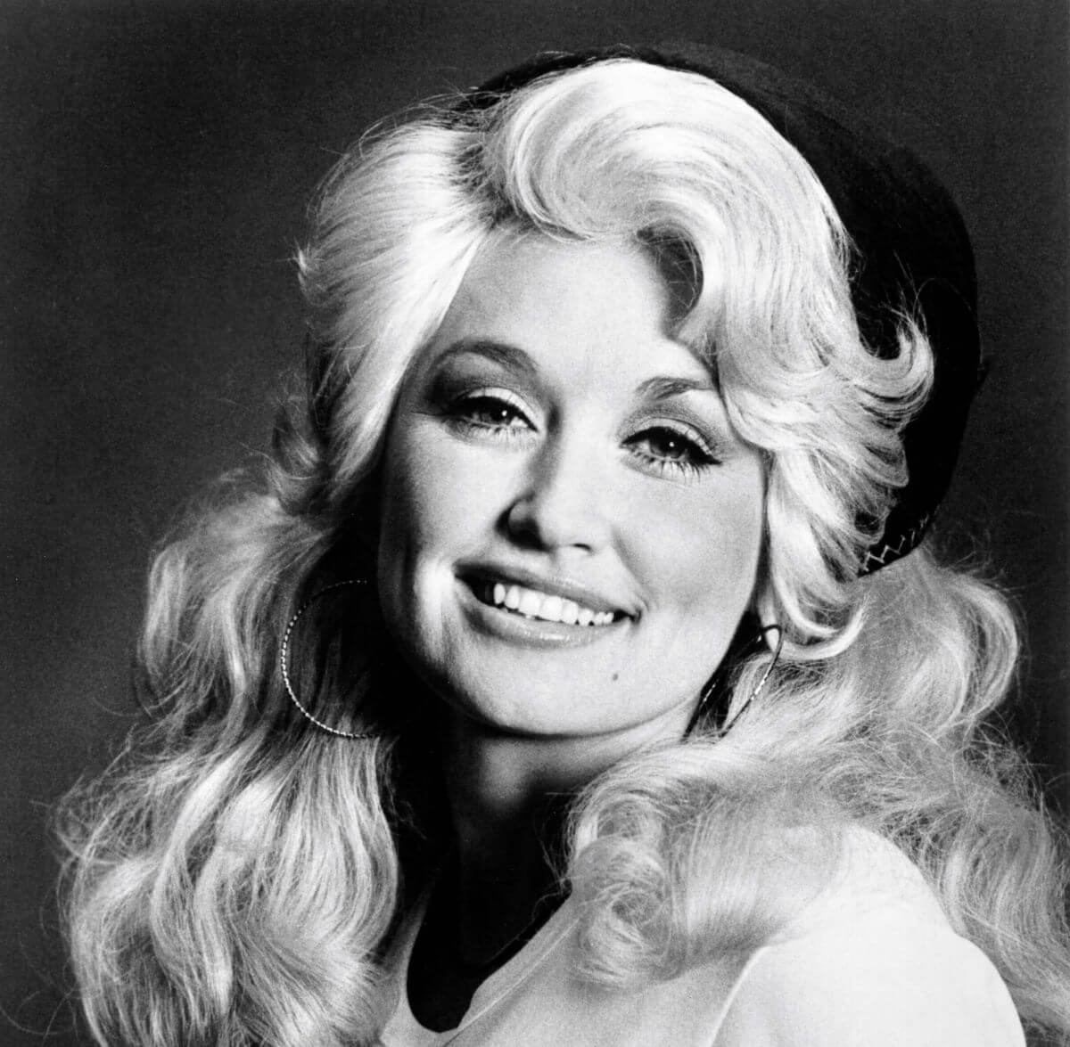 A black and white picture of Dolly Parton wearing hoop earrings.