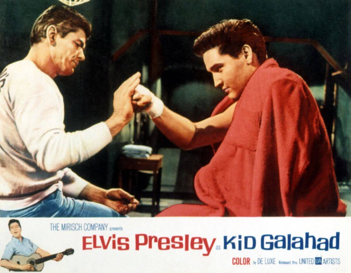 Elvis pushes his fist into Charles Bronson's hand in a still from 'Kid Galahad.' Elvis has a red blanket around him.