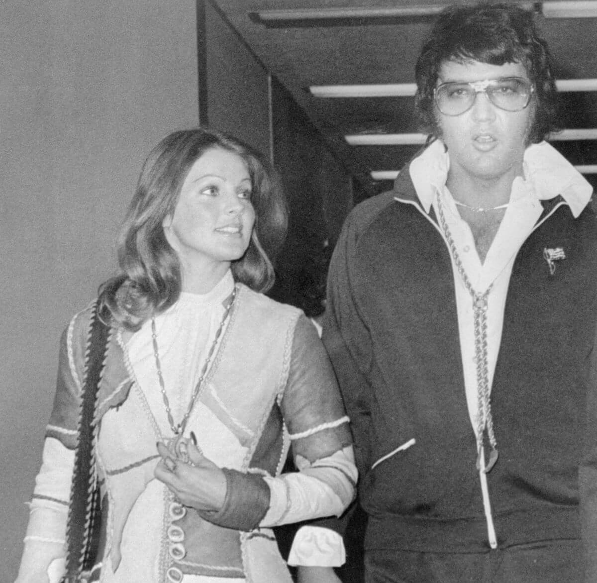 A black and white picture of Priscilla and Elvis Presley leaving a courthouse together.