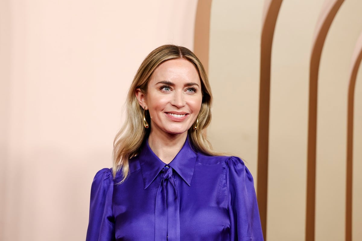 Emily Blunt posing at the 2024 Oscars Nominees Luncheon Red Carpet in a blue dress.