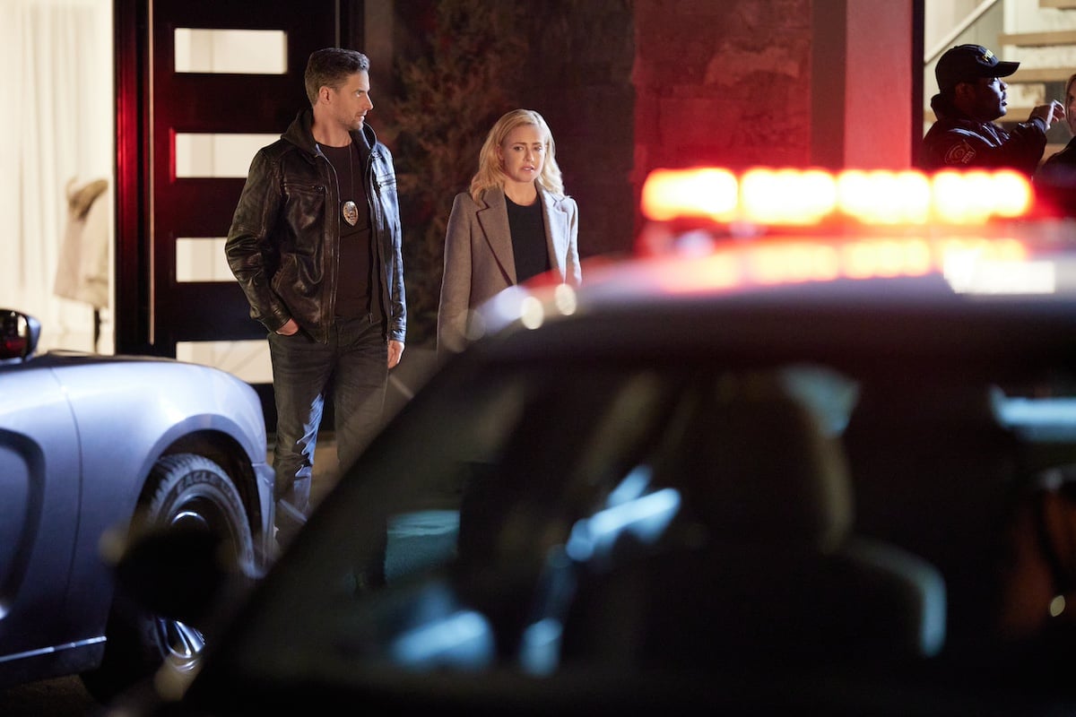 Brendan Penny and Amanda Schull standing next to a police car with flashing lights in Hallmark's 'Family Practice Mysteries: Coming Home'