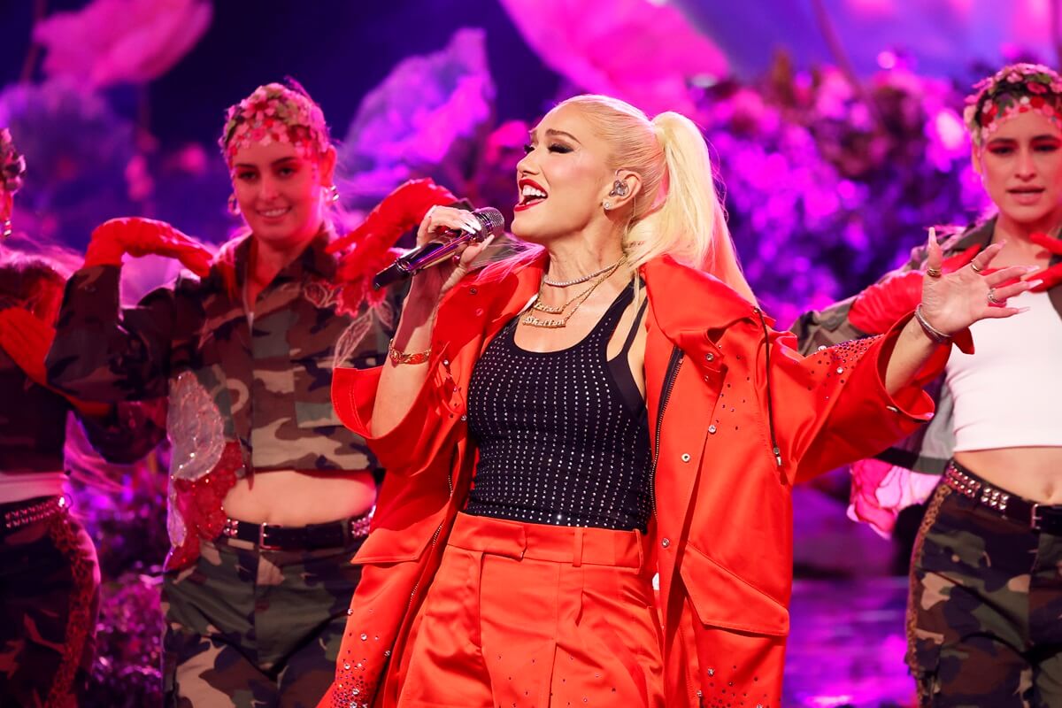Gwen Stefani singing on stage wearing a red and black outfit.