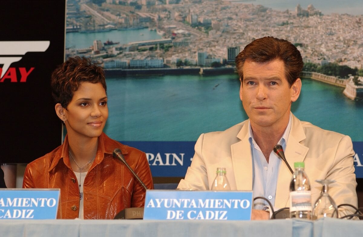 Halle Berry sitting down next to Pierce Brosnan at a James Bond press conference.