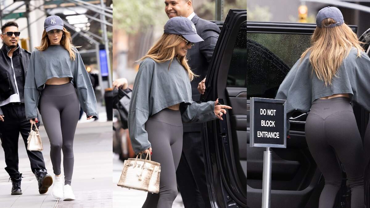 Singer Jennifer Lopez walks across an NYC street in gray leggins and a gray cropped tee shirt, showing her abs