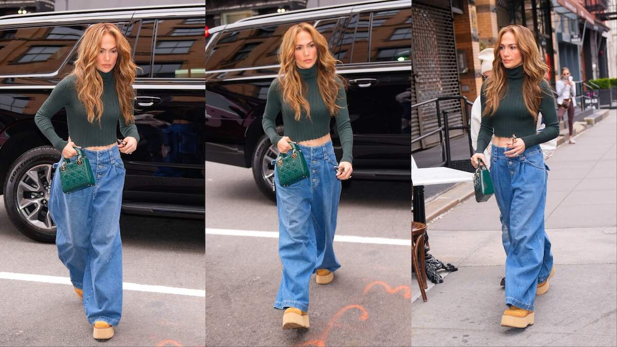 Singer Jennifer Lopez walks across an NYC street in baggy jeans and a green top, showing her abs