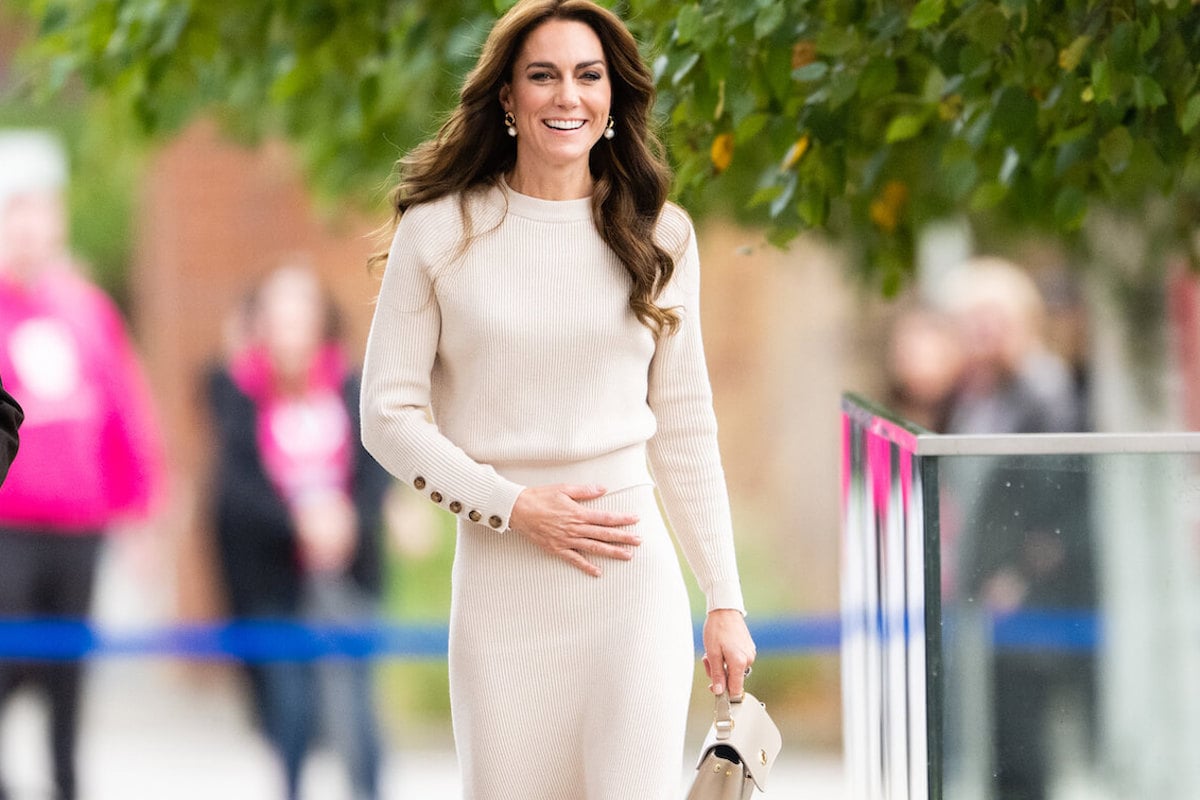 Kate Middleton, who keeps four items in her purse, smiles carrying a cream handbag and matching cream outfit.
