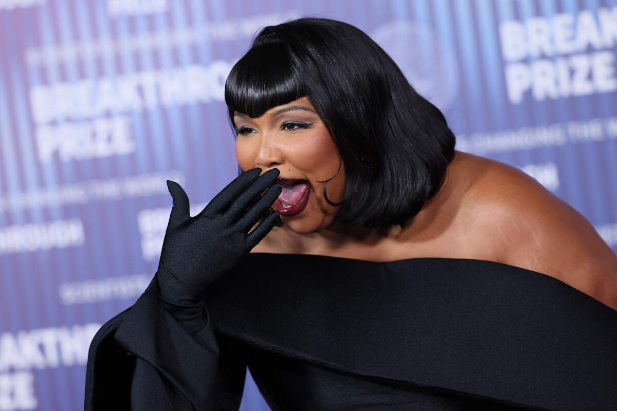 Singer Lizzo laughs while wearing a black dress and gold bangles at the 2024 Breakthrough Prize Ceremony