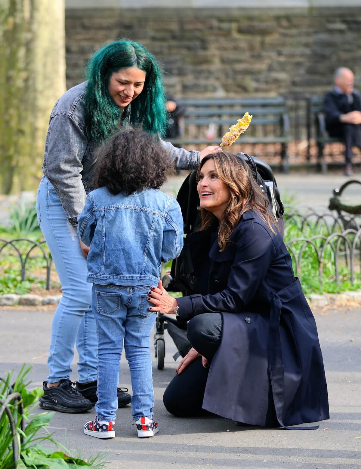 Mariska Hargitay and a woman with green hair talk to a little girl with her back to the camera