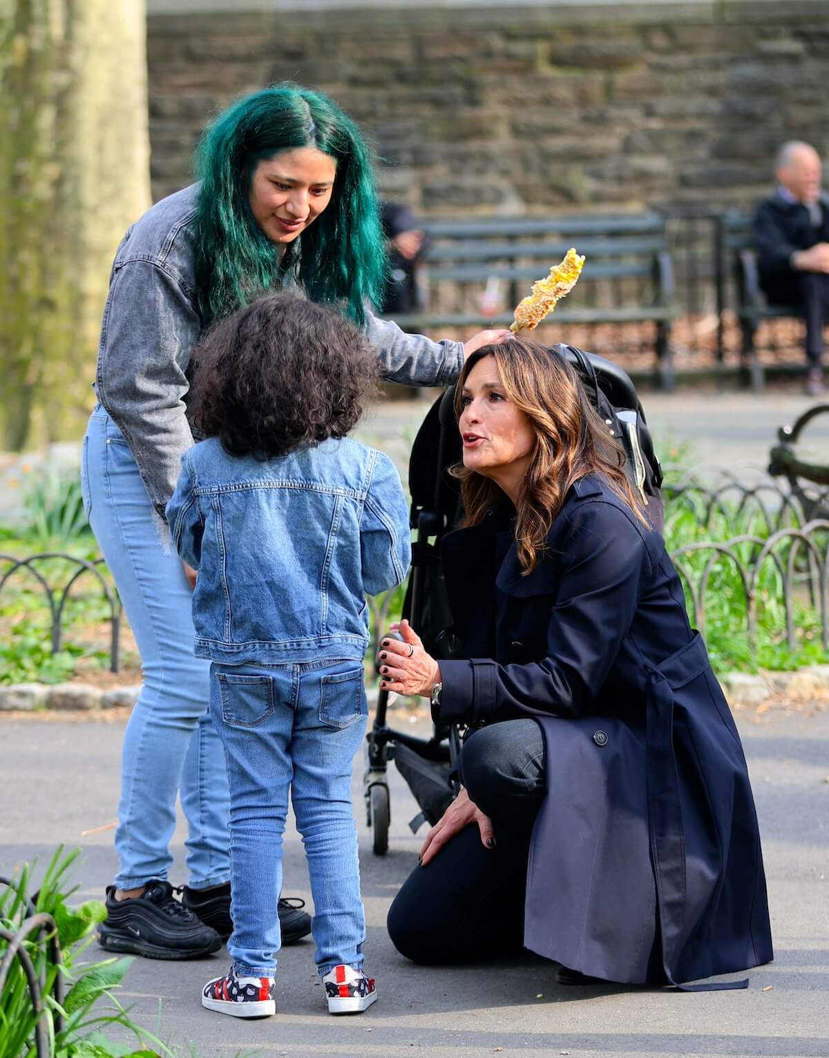 Mariska Hargitay and a woman with green hair talk to a little girl with her back to the camera