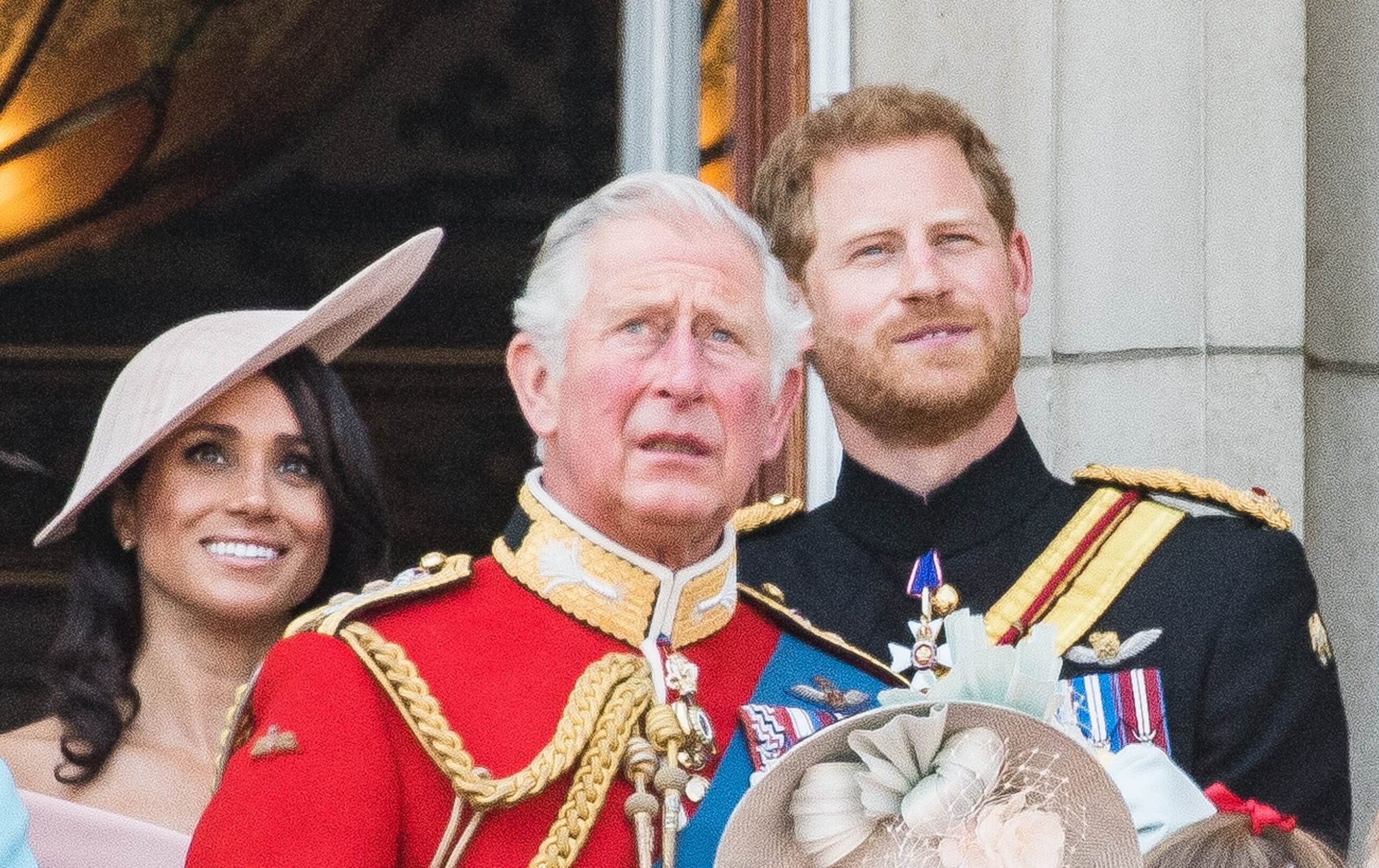 King Charles stands in front of Meghan Markle and Prince Harry