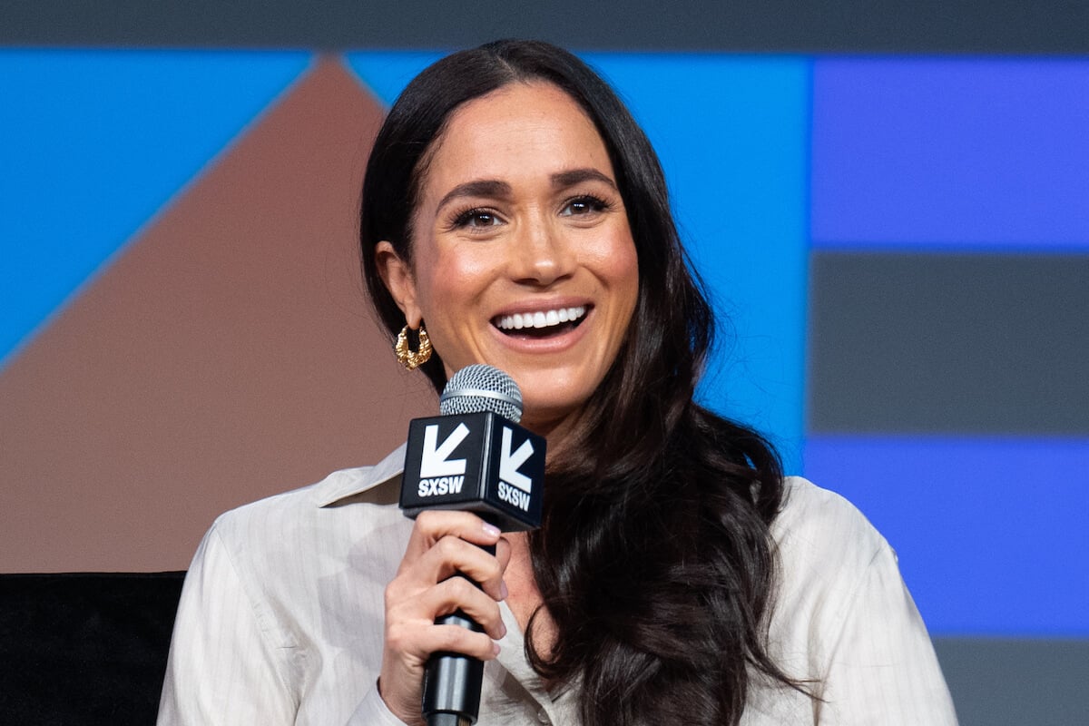Meghan Markle, whose American Riviera Orchard lifestyle brand must leverage celebrity connections to be successful, smiles as she holds a microphone at SXSW