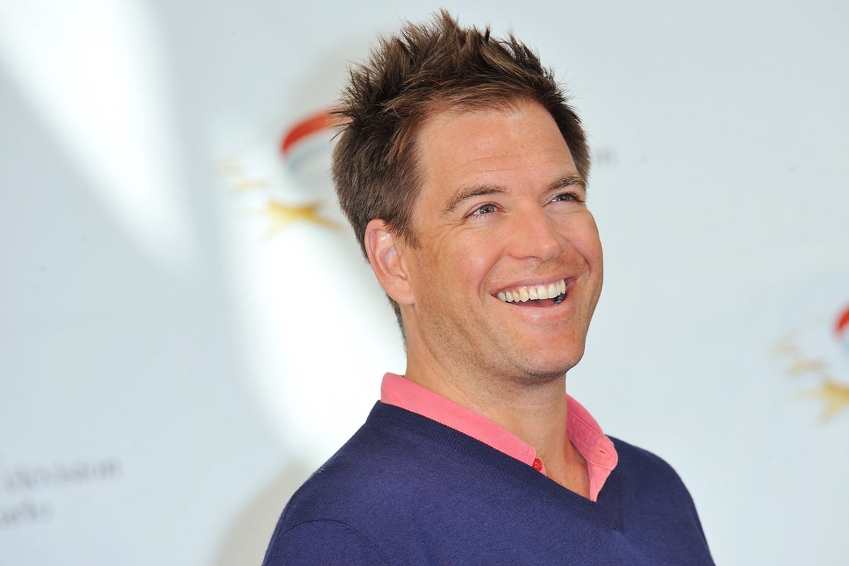 Michael Weatherly smiling in a blue sweater and while at an 'NCIS' photocall.