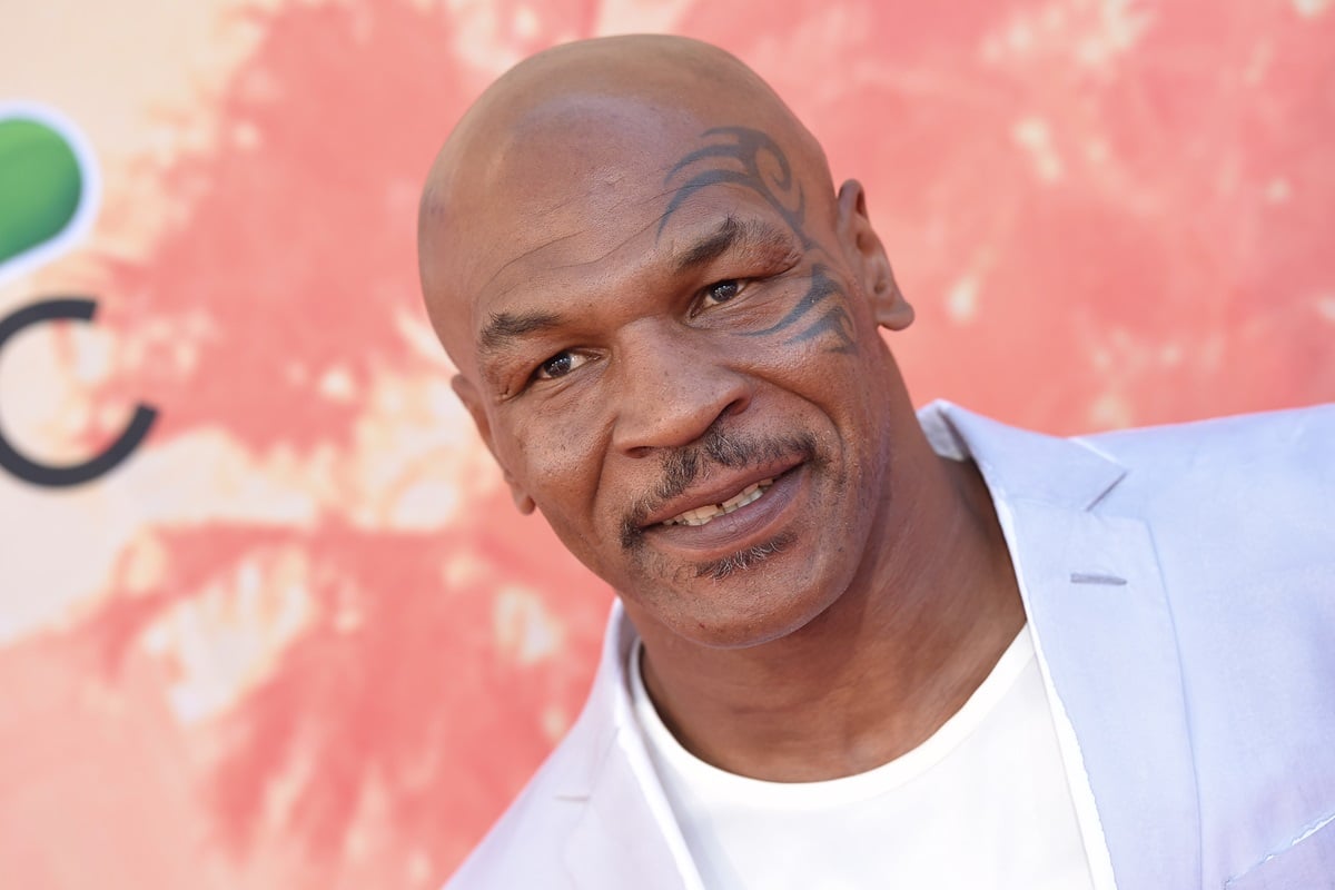 Mike Tyson posing at the 2015 iHeartRadio Music Awards while wearing a blue blazer and white shirt.