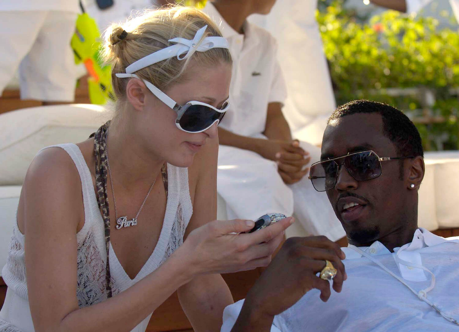Paris Hilton sitting next to Sean 'P. Diddy' Combs outside. They're both wearing white.