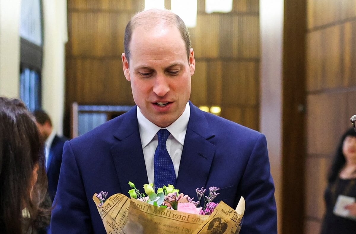 Prince William receives a bouquet of flowers for his wife, Kate Middleton, during a visit to the Western Marble Arch Synagogue