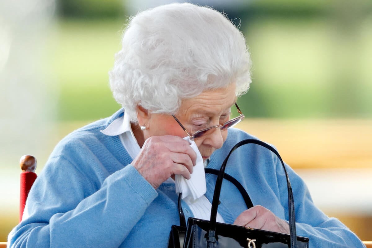 Queen Elizabeth II reaches into her handbag