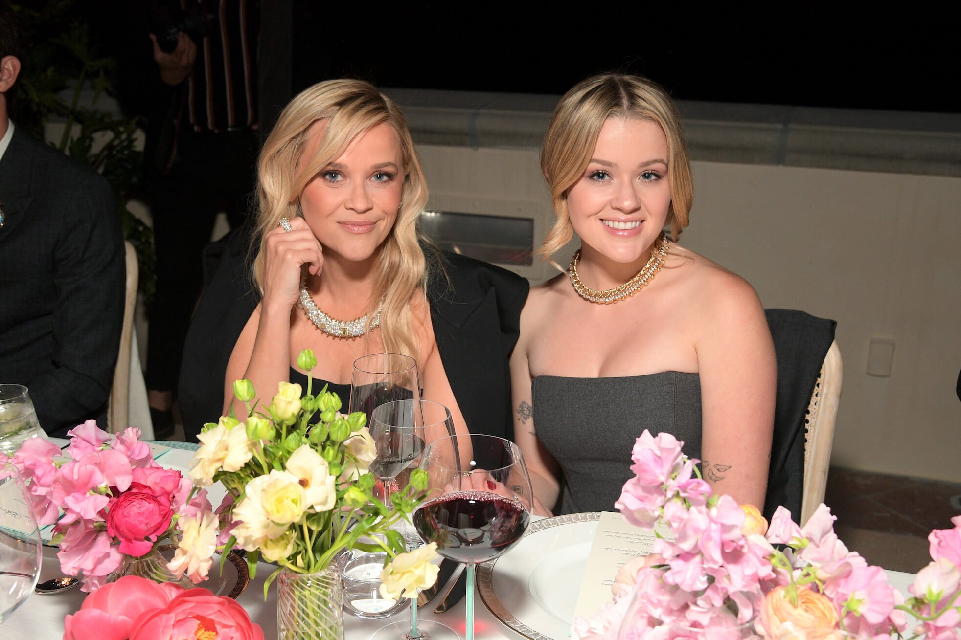 Reese Witherspoon and Ava Phillippe attend a Tiffany & Co. celebration together. They're sitting at a table wearing similar black strapless gowns.
