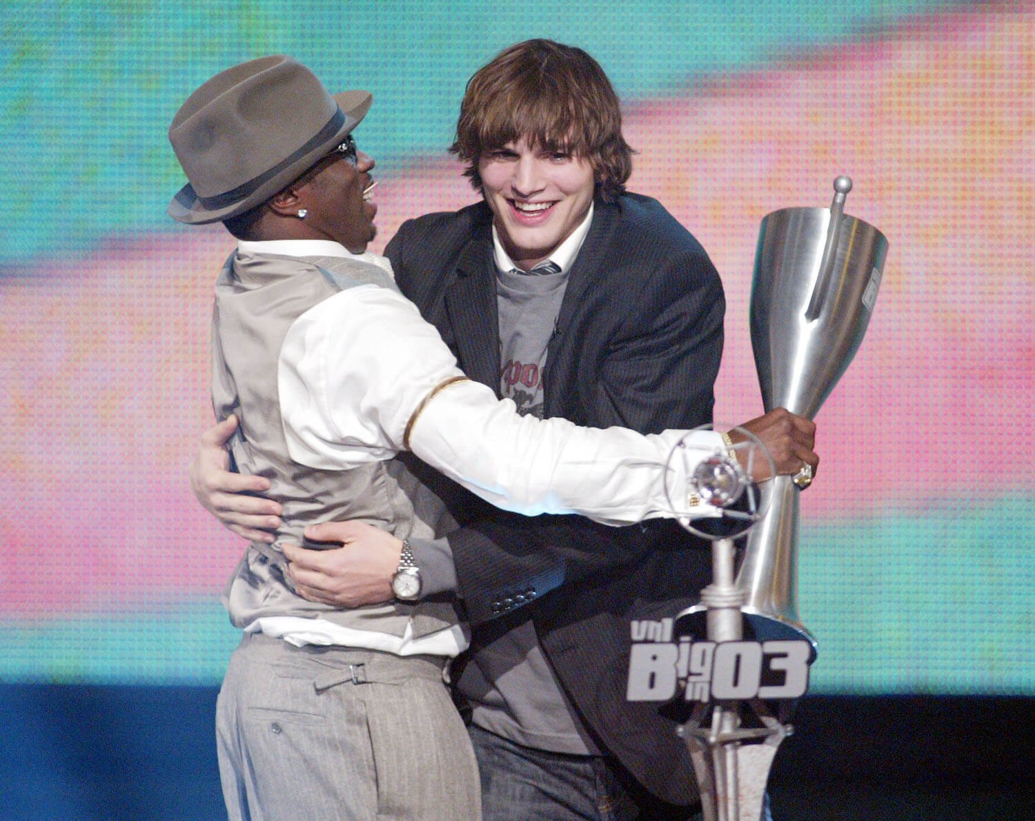 Sean 'P. Diddy' Combs hugging Ashton Kutcher on stage while holding an award in 2003