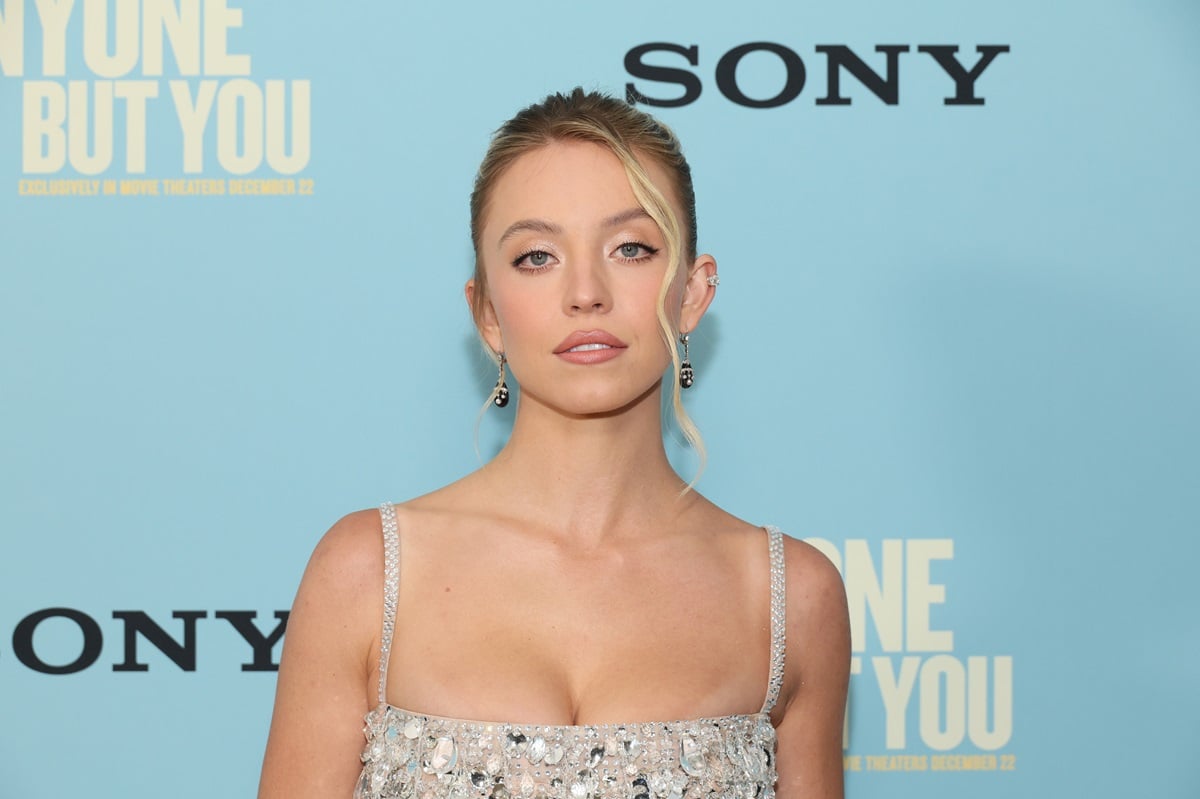Sydney Sweeney posing at the premiere of 'Anyone But You' while wearing a silver dress.