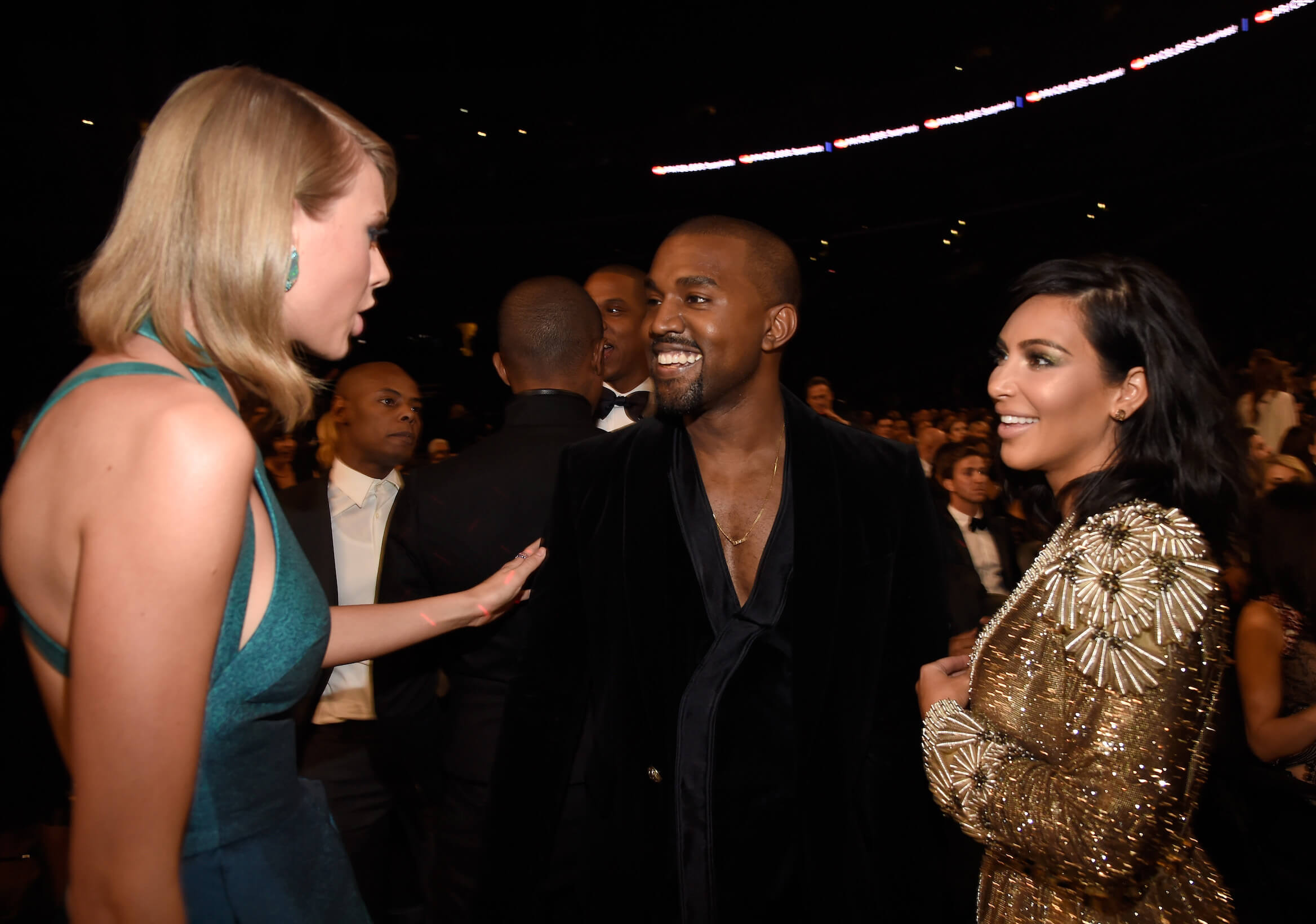 Taylor Swift speaking to Kanye West and Kim Kardashian at the Grammy Awards in 2015