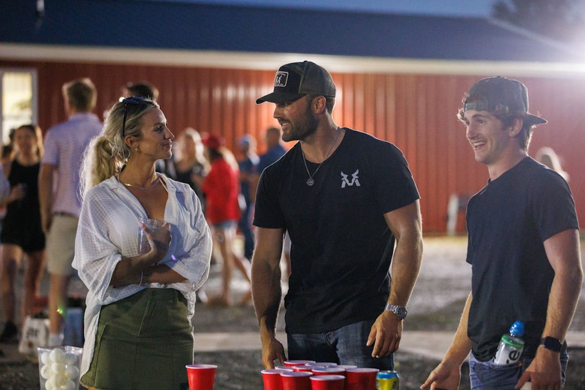 Three people standing outside and talking with red Solo cups in the foreground