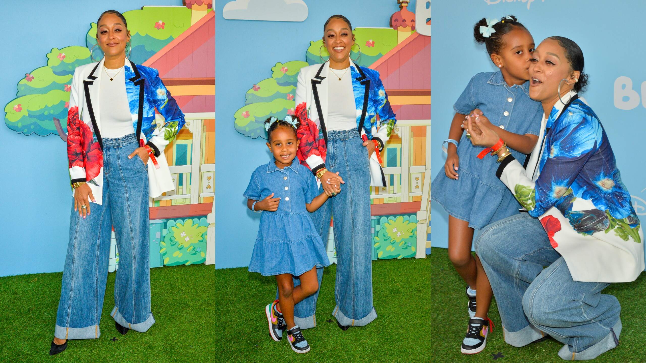 Wearing wide leg jeans, actor Tia Mowry and daughter Cairo smile for cameras at a Bluey event in 2024