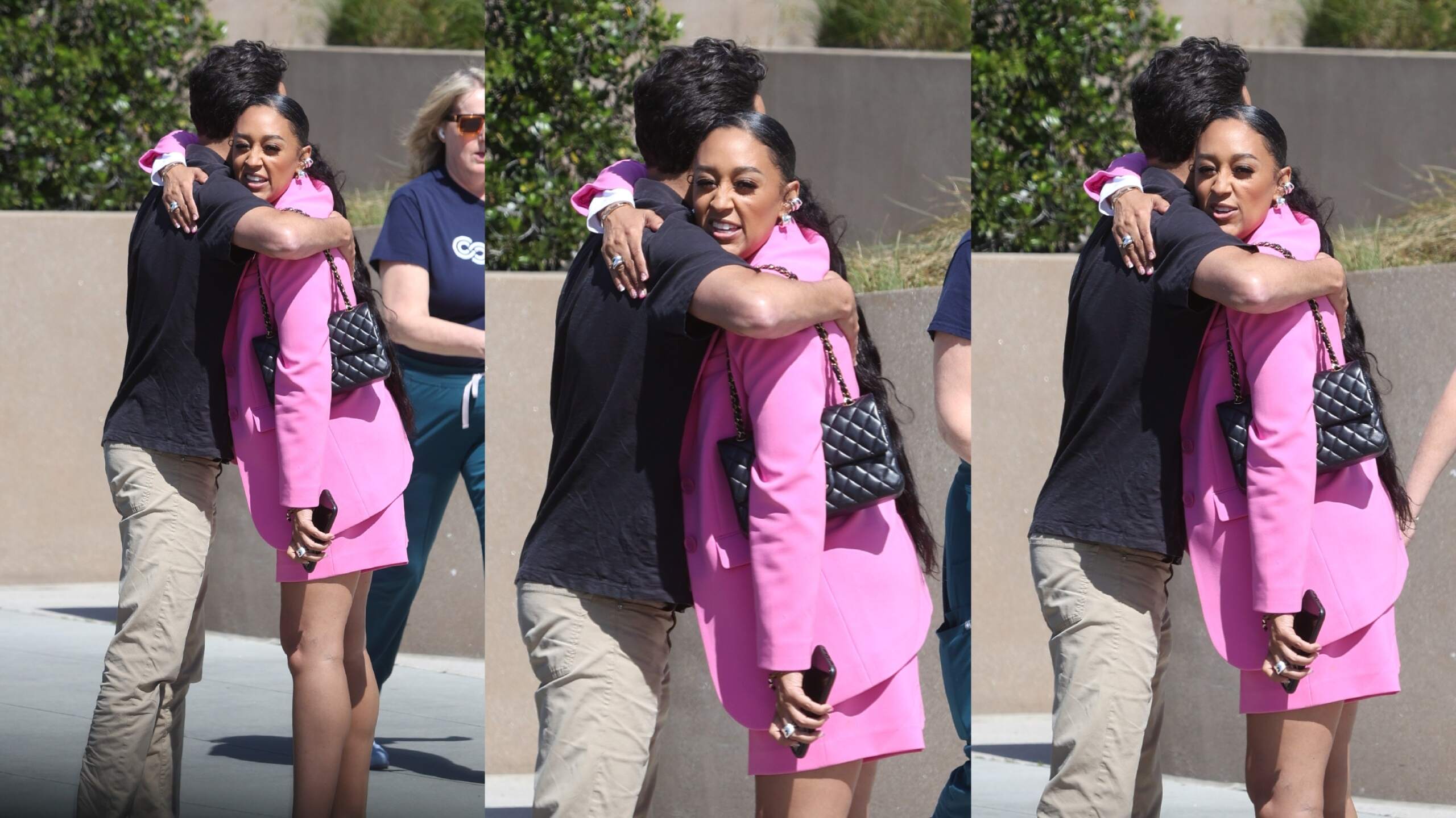 Wearing a pink blazer and matching skirt, Tia Mowry hugs an unidentified man