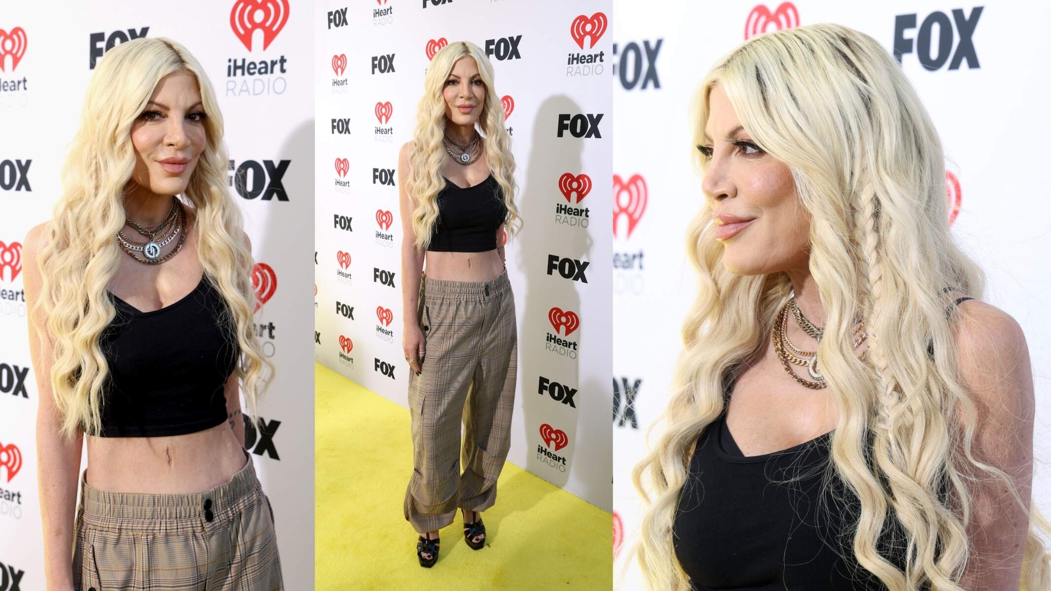 Wearing a black tank top and plaid pants, Tori Spelling smiles for cameras at the 2024 iHeartRadio Music Awards