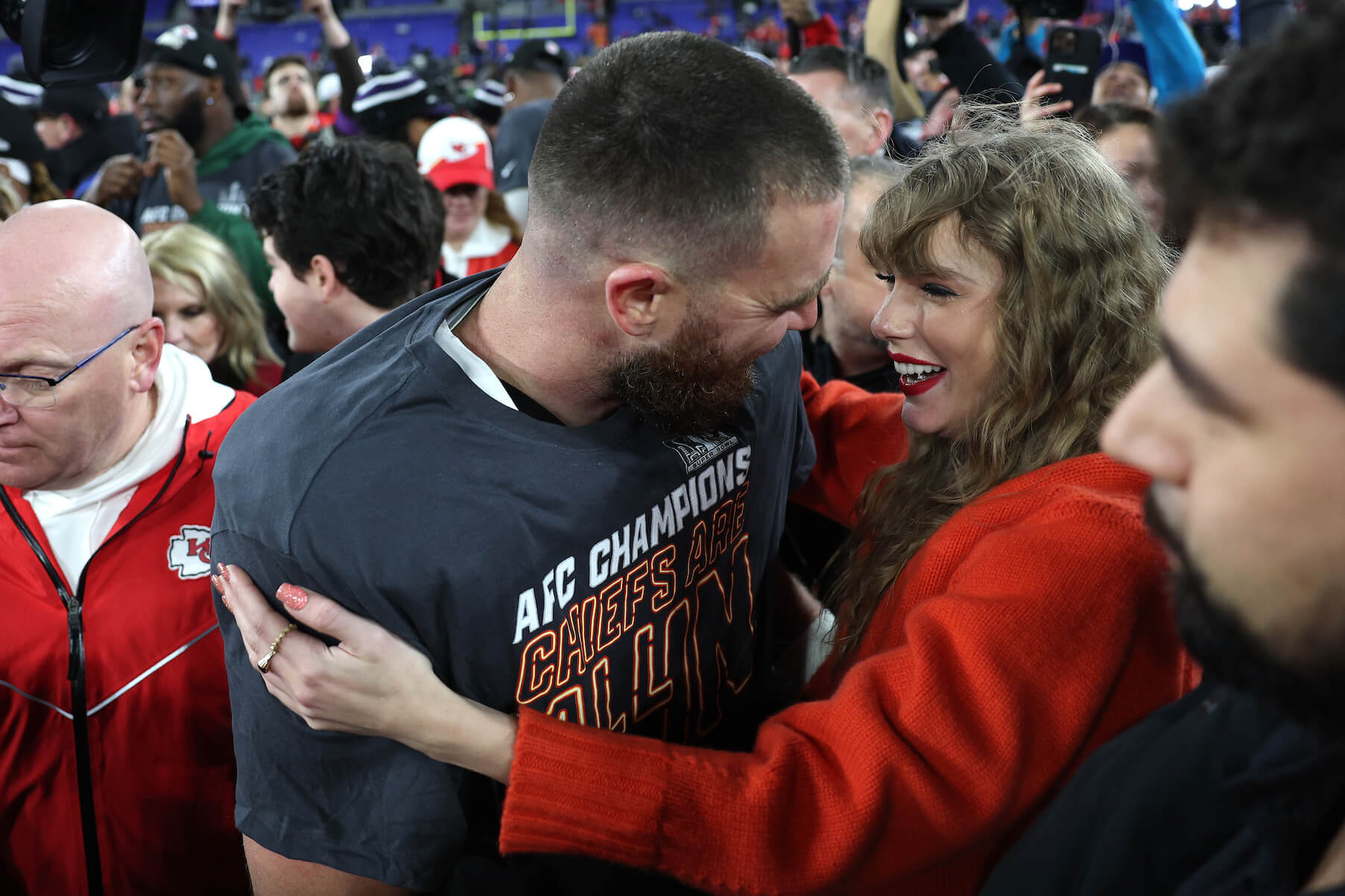 Travis Kelce and Taylor Swift embracing, smiling and looking at each other at a Kansas City Chiefs game
