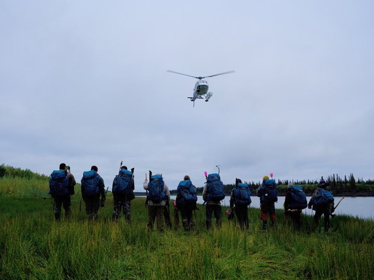 Group photo of 'Alone' Season 11 cast with helicopter in sky