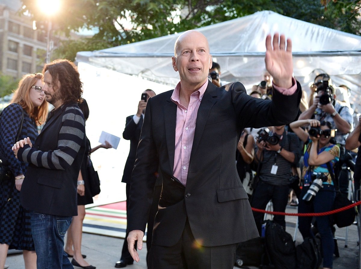 Bruce Willis posing in a suit at the premiere of 'Looper'.