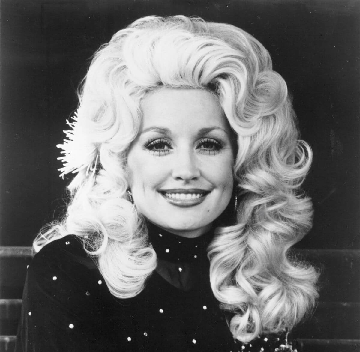 A black and white picture of Dolly Parton wearing a turtleneck and smiling.