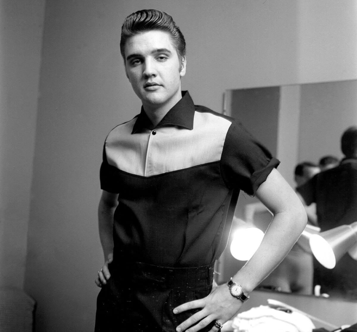 A black and white picture of Elvis standing with his hands on his hips.