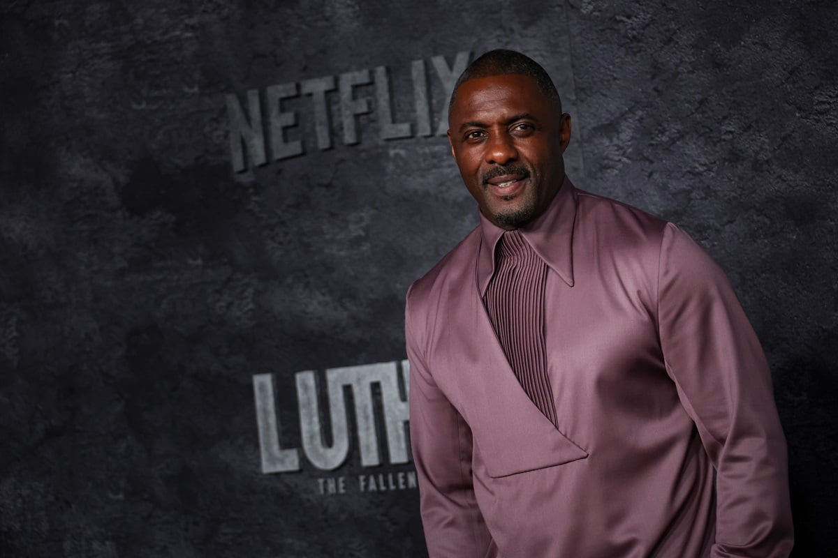 Idris Elba posing in a purple outfit at the premiere of 'Luther: The Fallen Sun'.