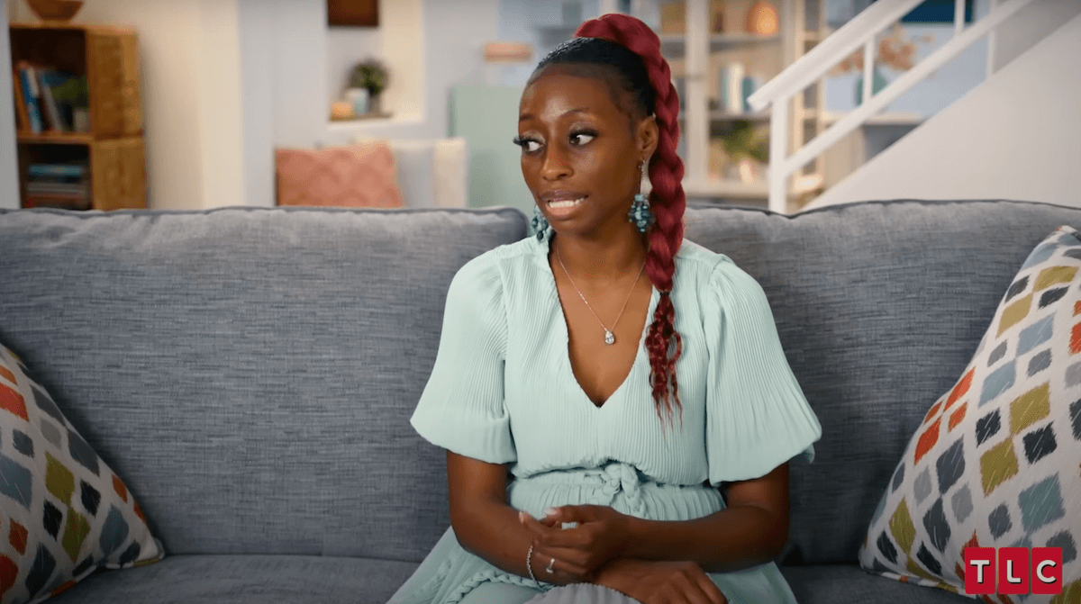 Karen Derrico of 'Doubling Down With the Derricos' sitting on a couch and wearing a pale blue dress