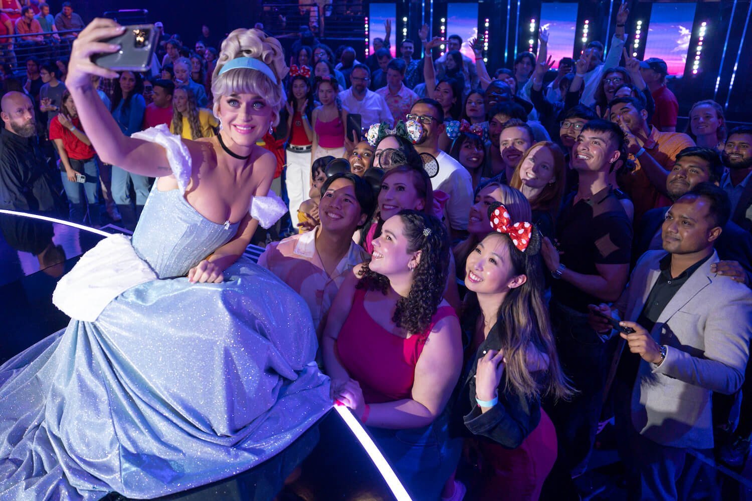 Katy Perry dressed as Cinderella for 'American Idol' Season 22 Disney Night. She's kneeling toward the crowd and taking a selfie.