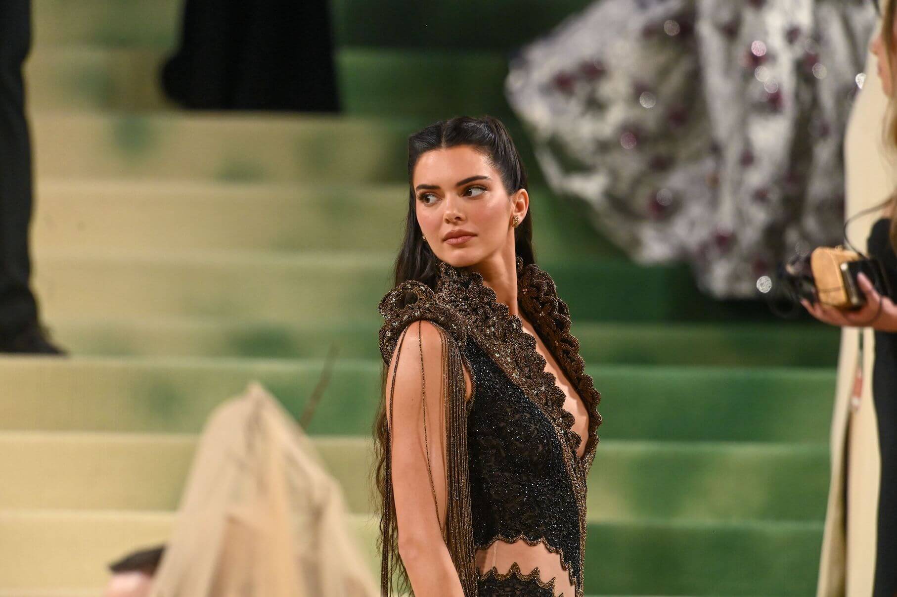 Kendall Jenner looking over her shoulder while wearing a long black gown at the 2024 Met Gala