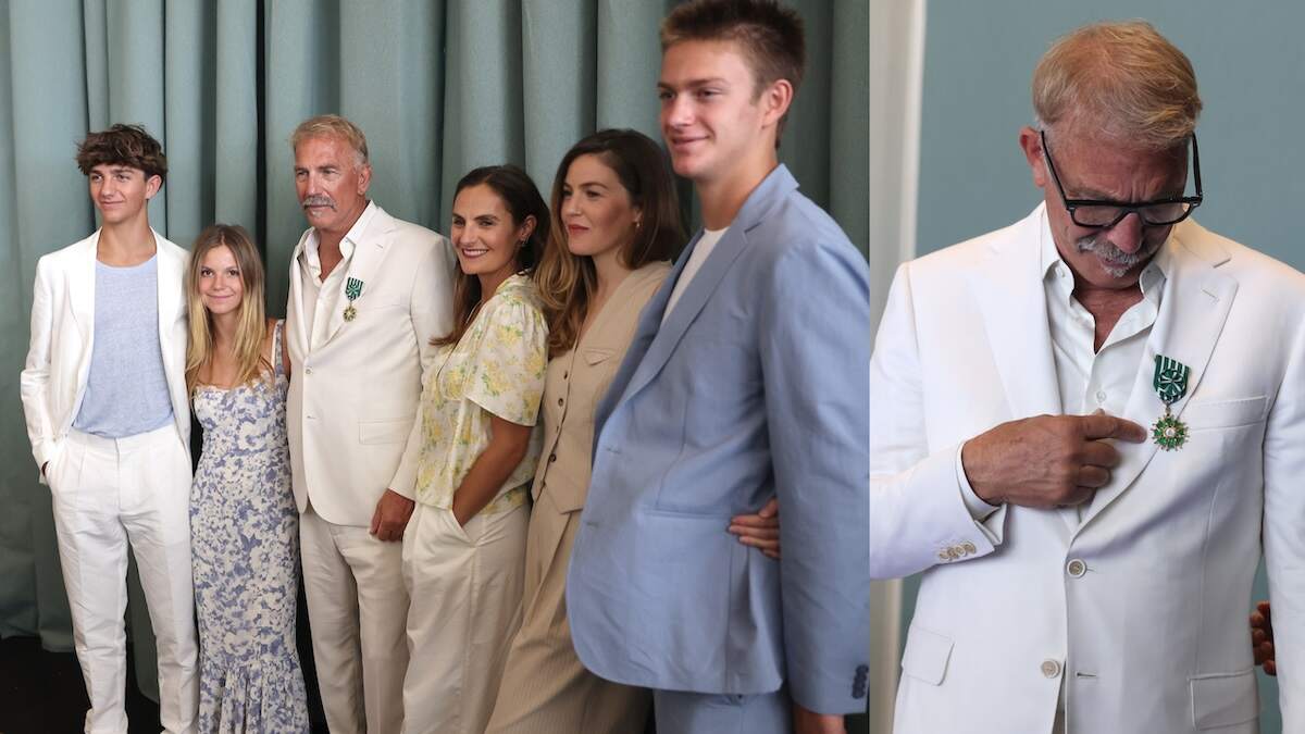 Wearing a white suit, Kevin Costner receives the Order of Arts and Letters from the Minister of Culture at the 77th annual Cannes Film Festival at Palais des Festivals