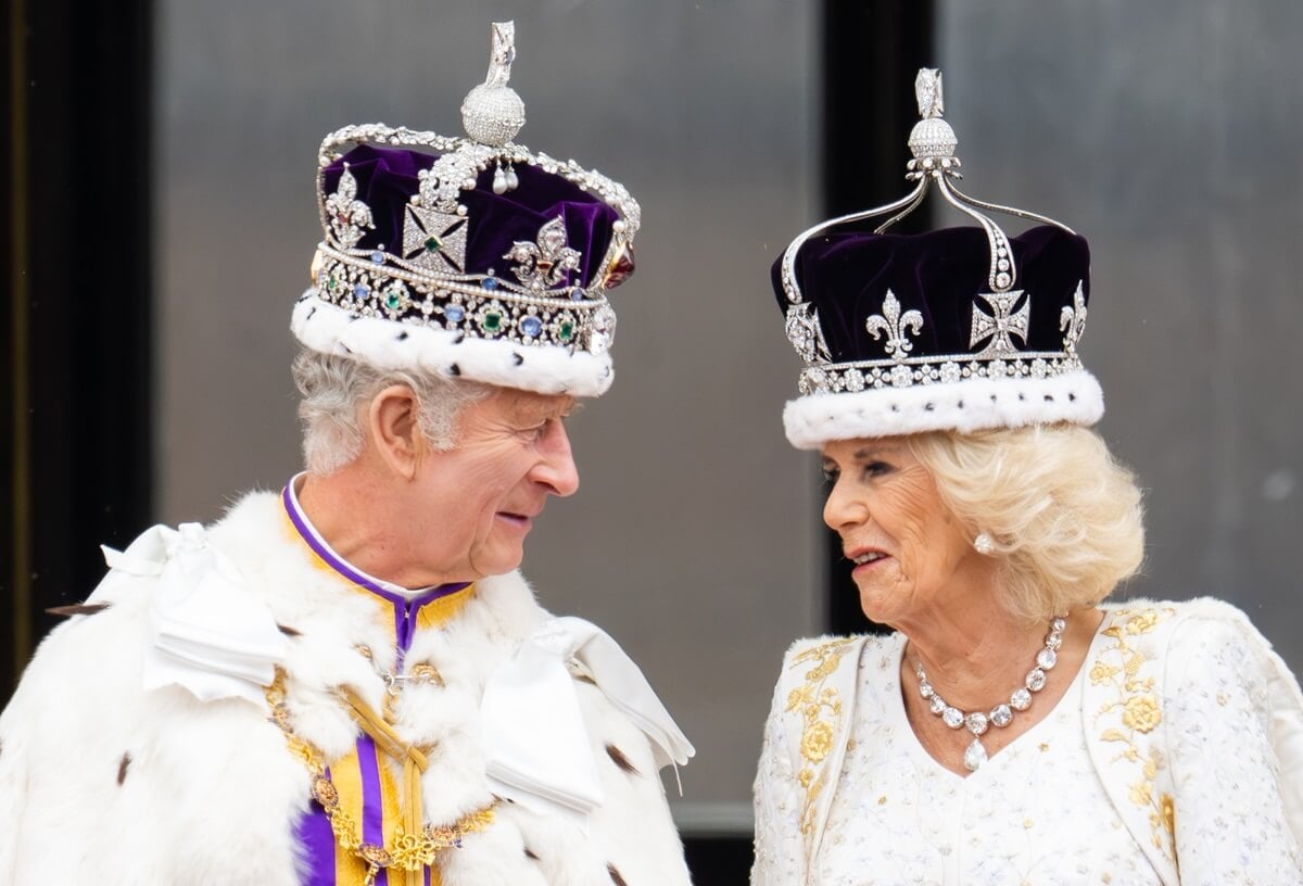 King Charles III and Queen Camilla speaking to each other on the balcony of Buckingham Palace following their Coronation