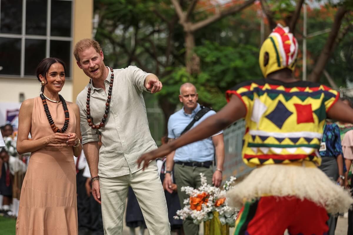 Meghan Markle and Prince Harry watch people dancing as they arrive at the Lightway Academy in Abuja  