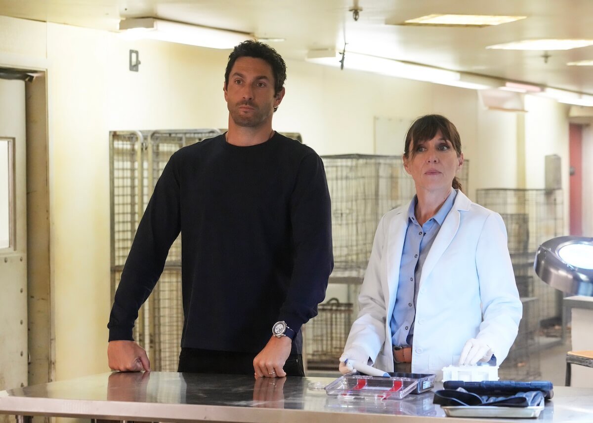 Boone stands next to a woman in a white lab coast in the 'NCIS: Hawai'i' series finale
