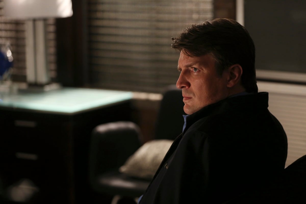 Nathan Fillion posing while sitting down in an episode of 'Castle'.