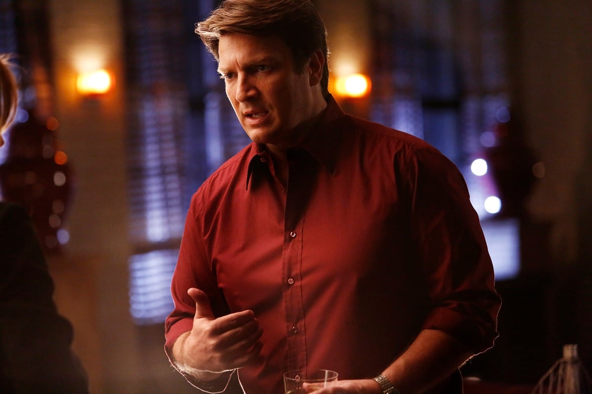 Nathan Fillion posing while wearing a red shirt in an episode of 'Castle'.