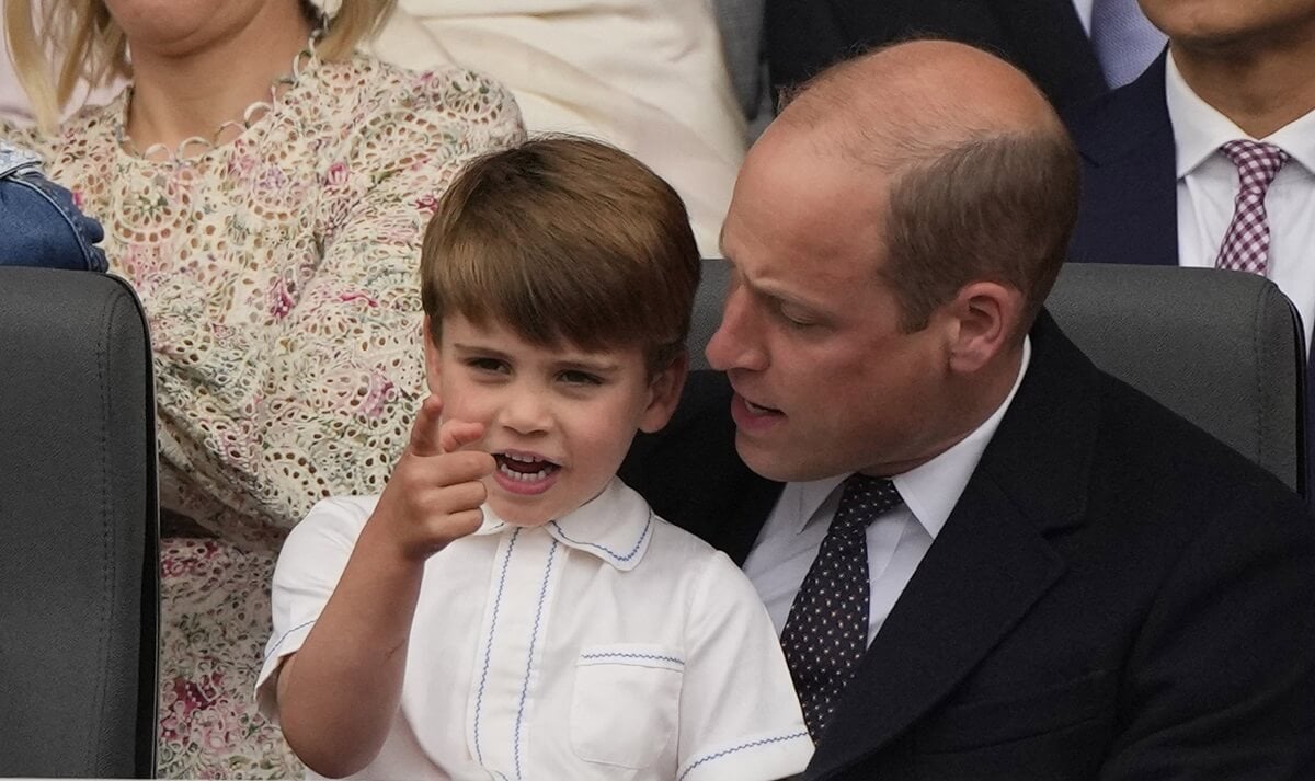 Prince Louis pointing at something as he sits in his dad Prince William's lap during the Platinum Pageant