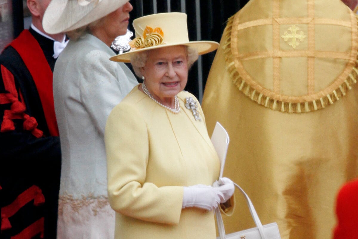 Queen Elizabeth II, who broke royal etiquette at Prince William and Kate Middleton's wedding, looks on wearing a yellow coatdress and hat at Westminster Abbey.